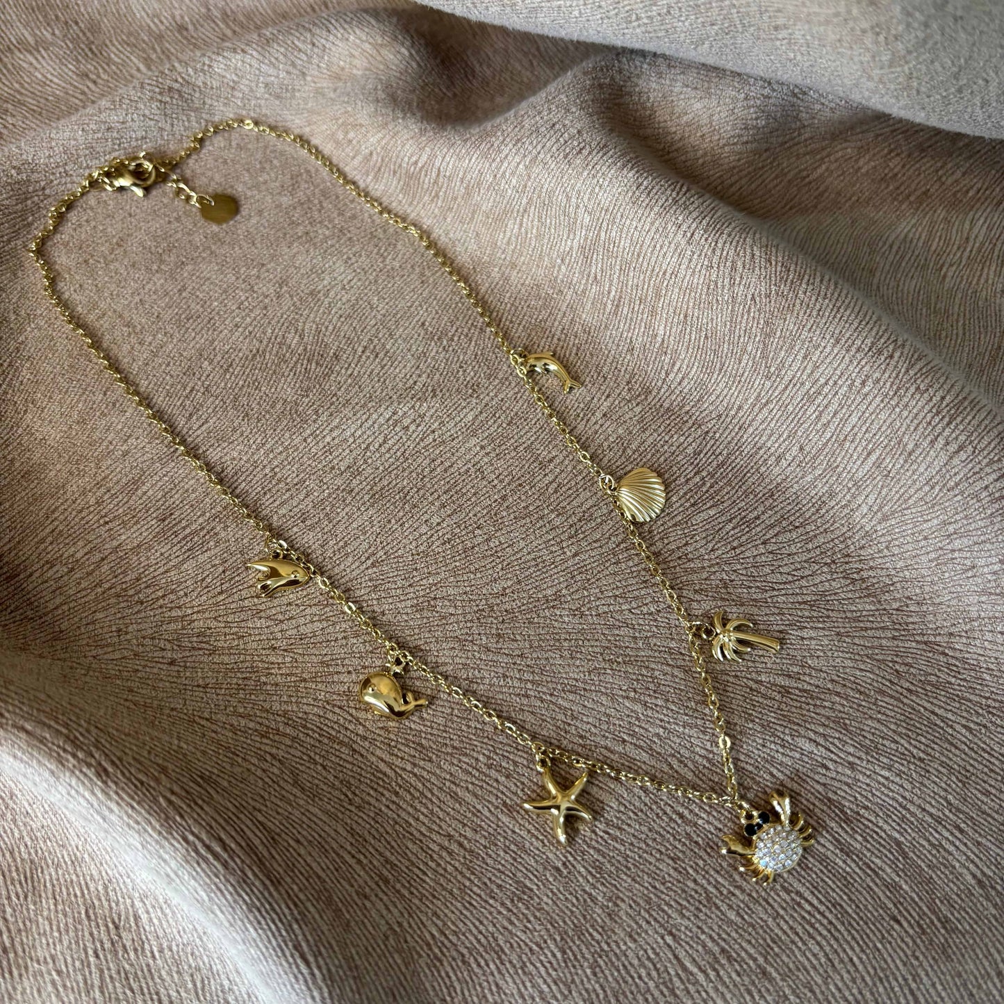 Collier à petits maillons dorés avec breloques coquillage palmier crabe étoile de mer et baleine en acier inoxydable vendu sur le site internet prêtes à briller