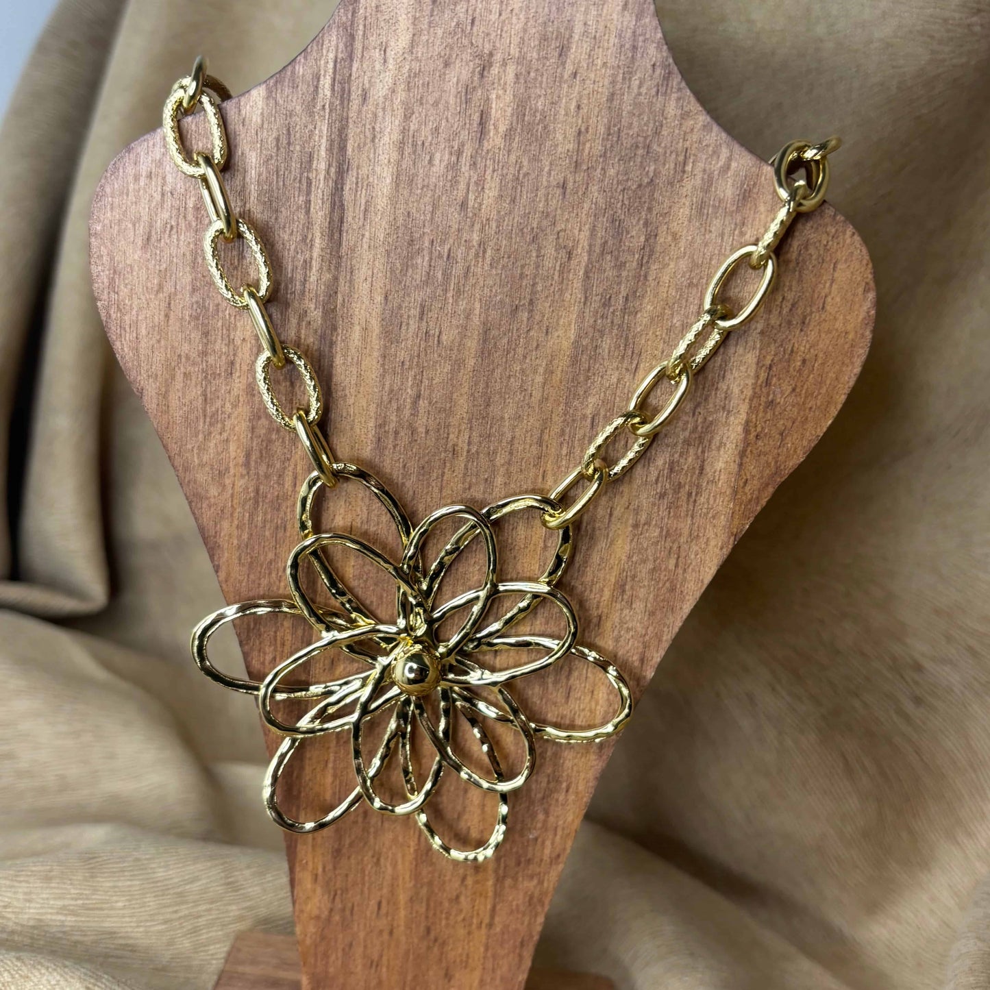 Vue de près d'un collier doré avec chaine grands maillons et pendentif en forme de fleur en acier inoxydable vendu sur le site internet prêtes à briller