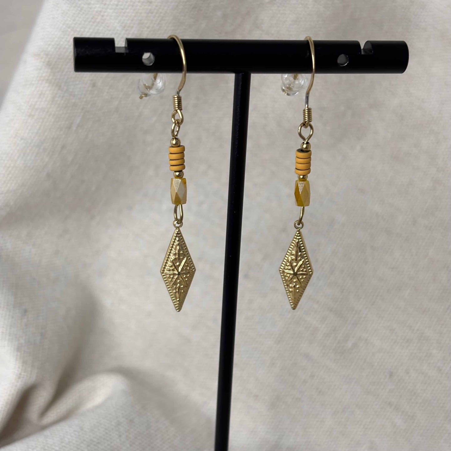 Boucles d'oreilles pendentif dorées avec perles plates oranges et breloque dorée rose des vents vendu sur le site internet prêtes à briller