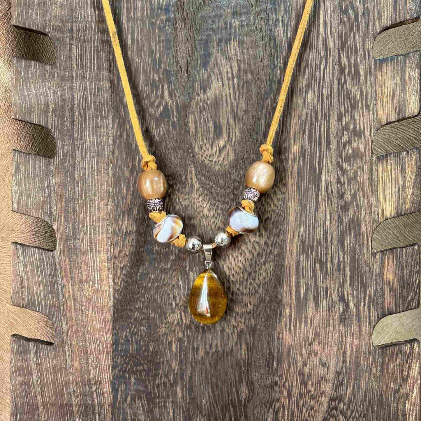 Vue de près d'un collier artisanal avec pendentif œil de tigre sur cordon cuir caramel perles verre et acier Collier artisanal avec pendentif œil de tigre sur cordon cuir caramel perles verre et acier bijou unique vendu sur le site internet prêtes à briller