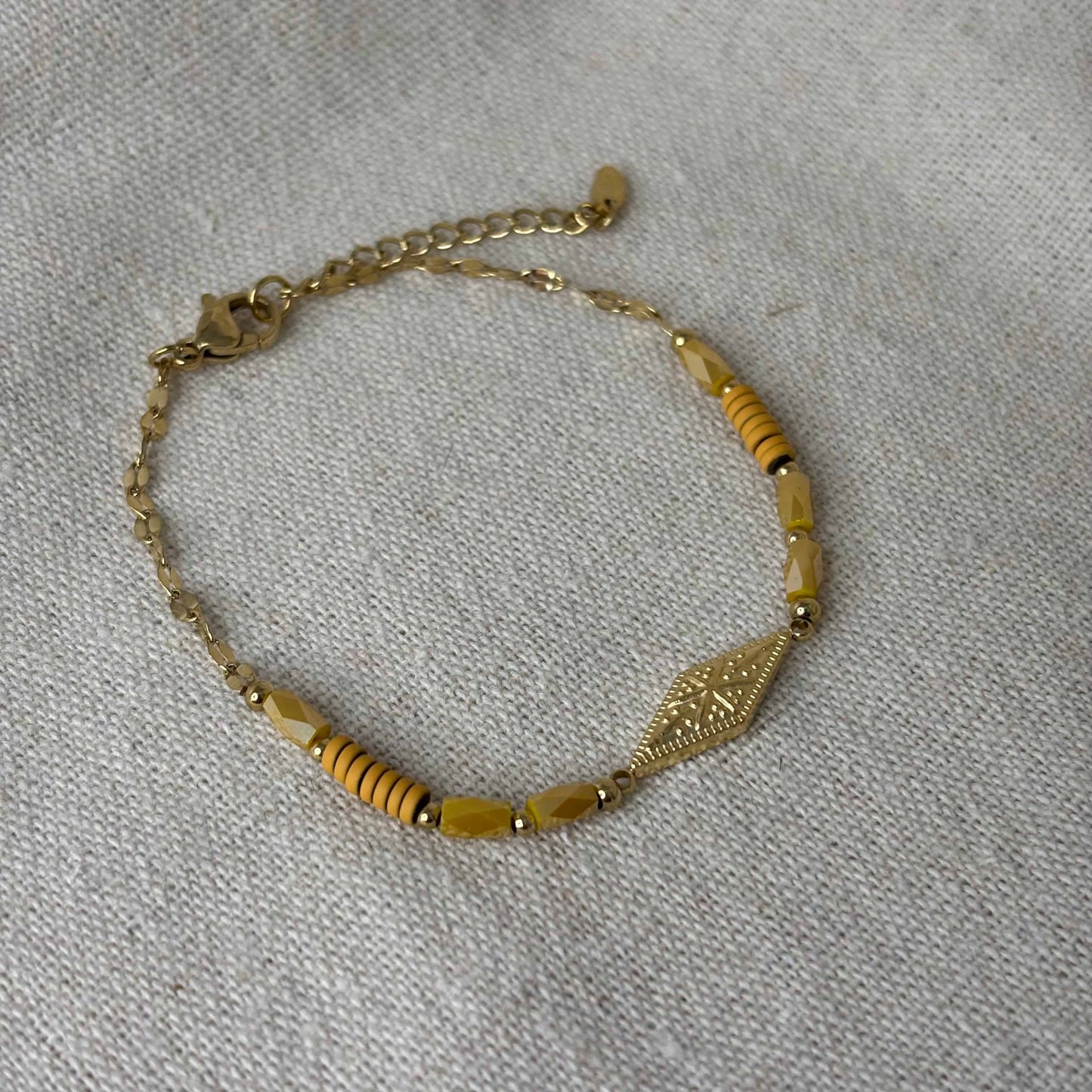 Bracelet doré à mailles fines avec des perles saumon et motif rose des vents dans un losange vendu sur le site internet prêtes à briller
