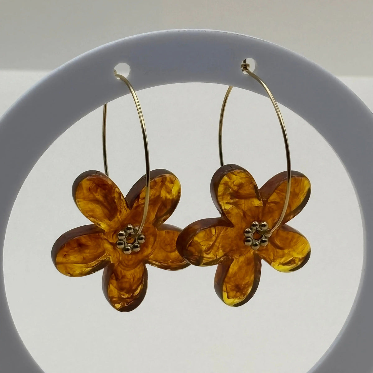 Des boucles d’oreilles en résine en forme de fleurs couleur ambre