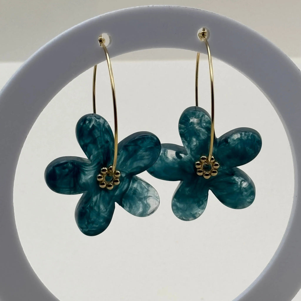 Des boucles d’oreilles en résine en forme de fleurs couleur bleue