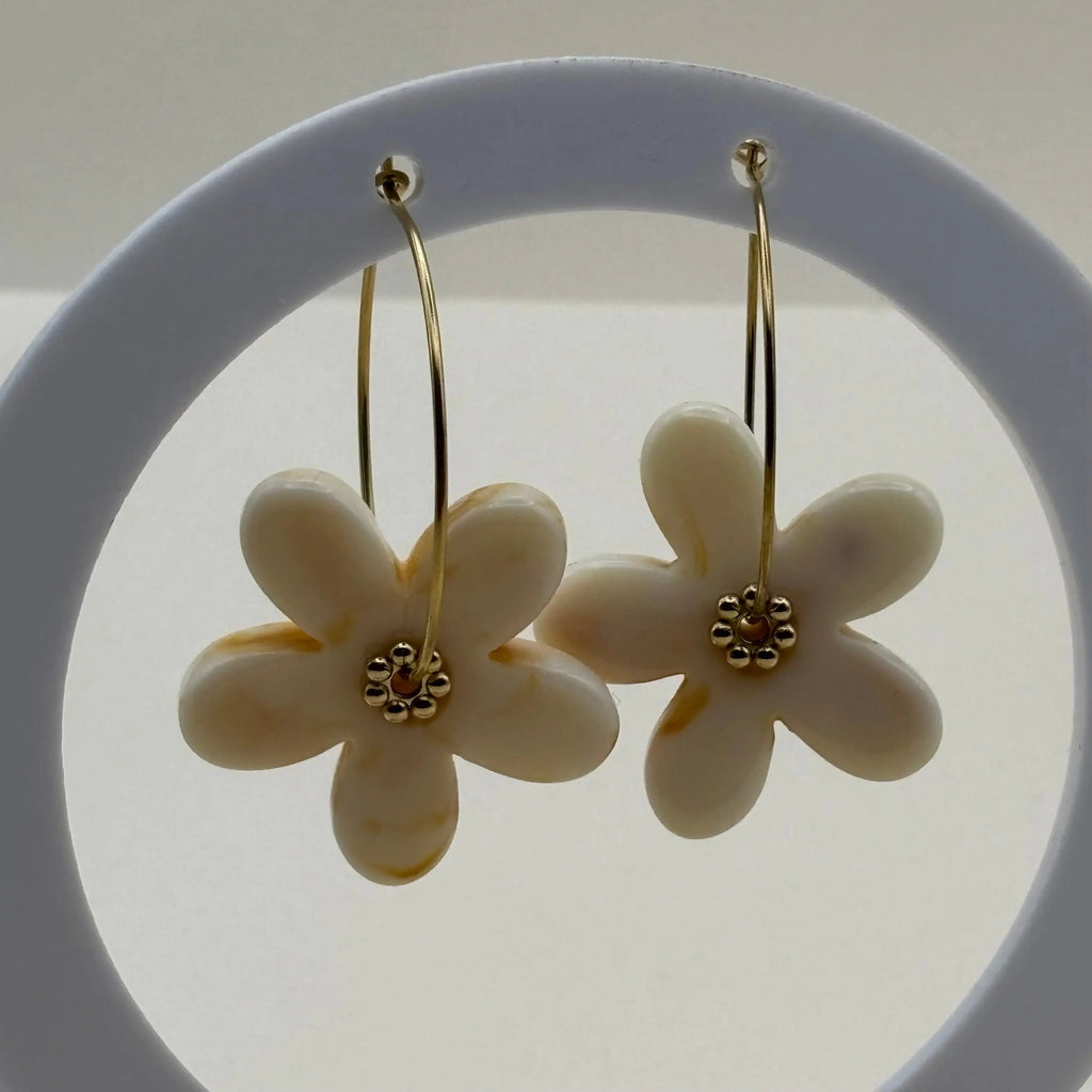 Des boucles d’oreilles en résine en forme de fleurs couleur écrues