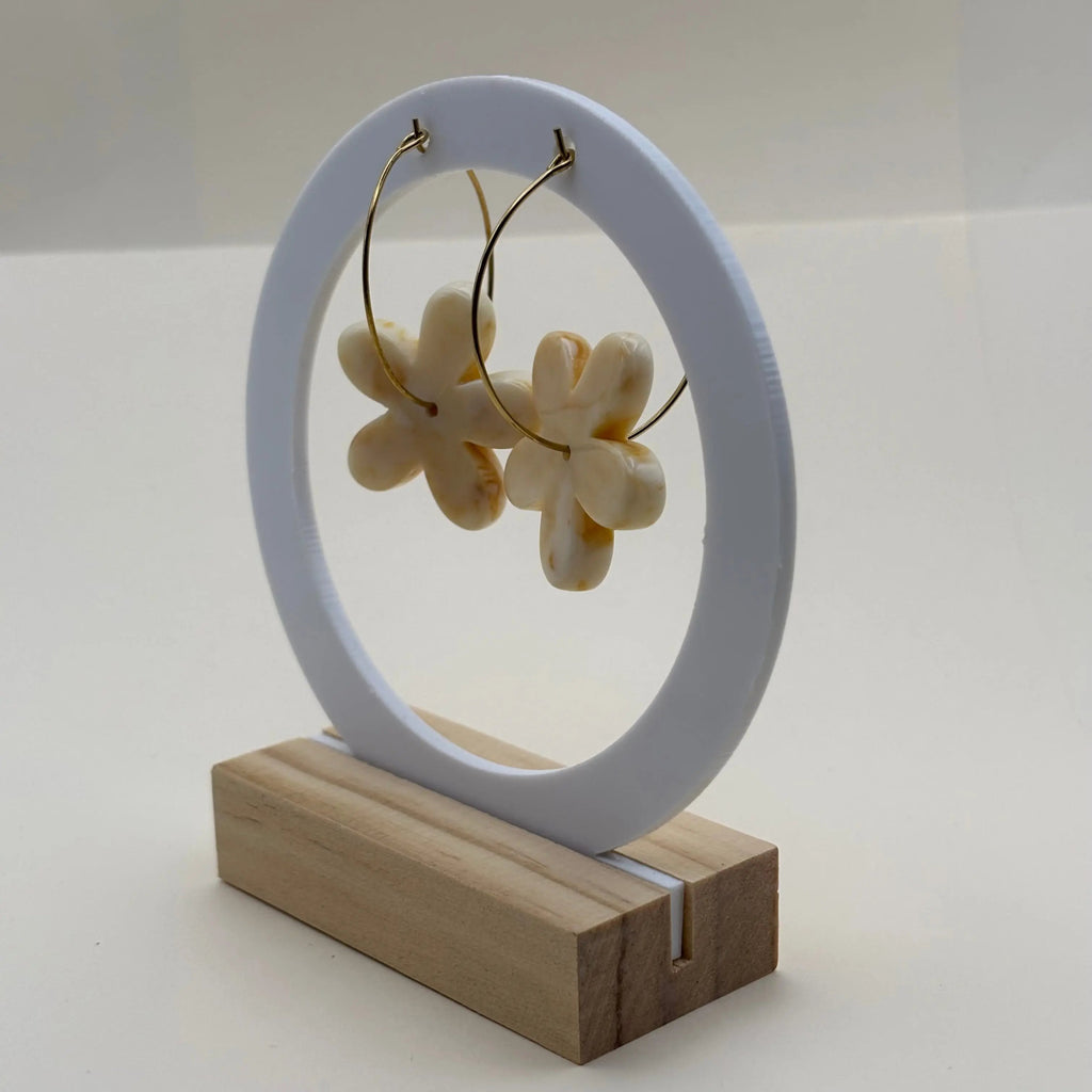 Une paire de boucles d’oreilles en résine en forme de fleurs couleur écrues