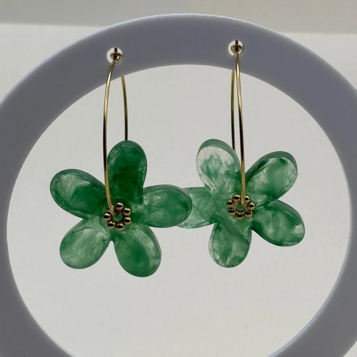 Des boucles d’oreilles en résine en forme de fleurs couleur vertes