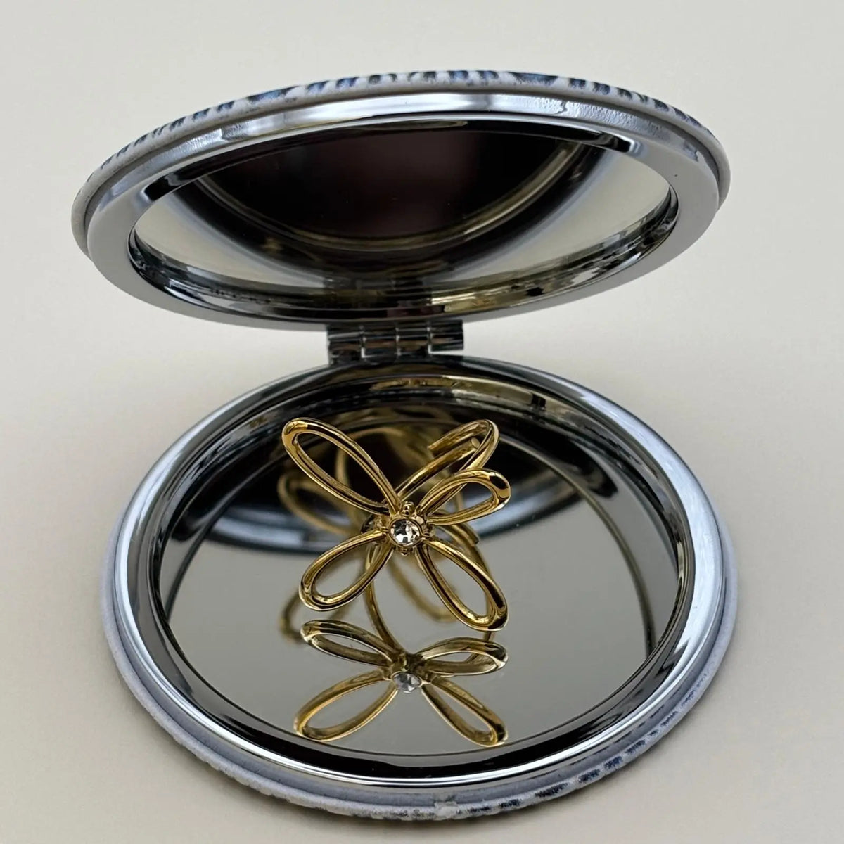 Bague dorée ajustable avec un motif de fleur a quatre pétales et strass en son centre