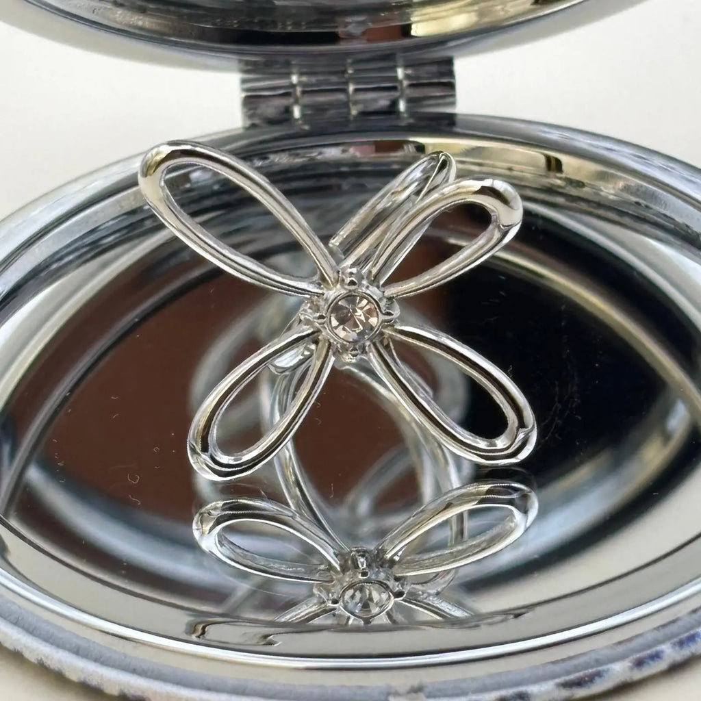 Bague couleur argentée ajustable avec un motif de fleur a quatre pétales et strass en son centre