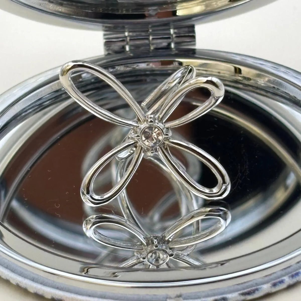 Bague couleur argentée ajustable avec un motif de fleur a quatre pétales et strass en son centre