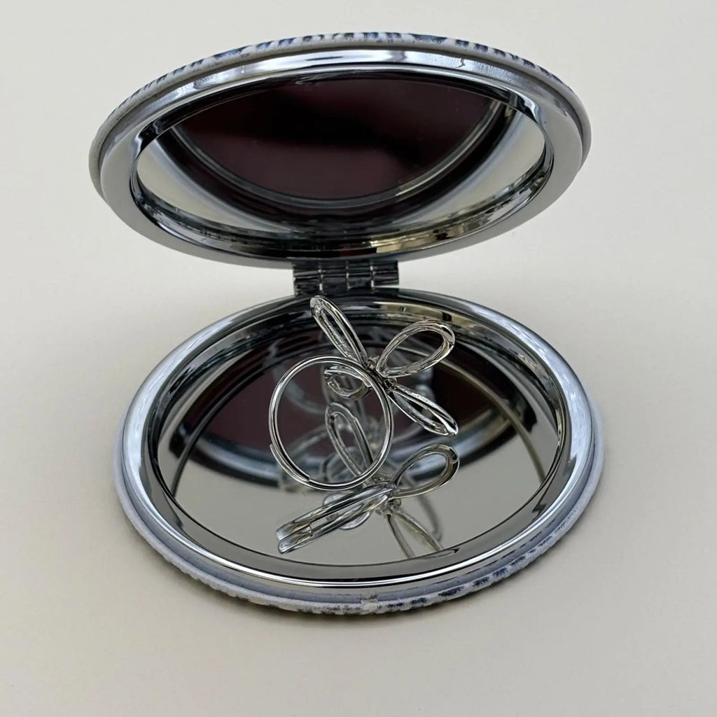 Bague argentée ajustable avec un motif de fleur a quatre pétales et strass en son centre