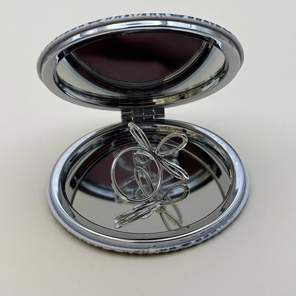 Bague argentée ajustable avec un motif de fleur a quatre pétales et strass en son centre