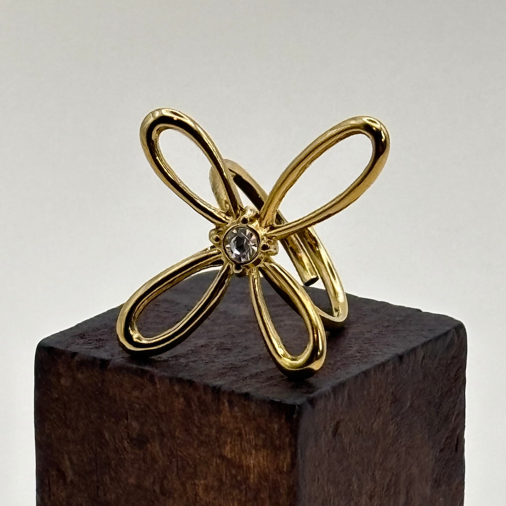 Bague dorée ajustable avec un motif de fleur a quatre pétales et strass en son centre