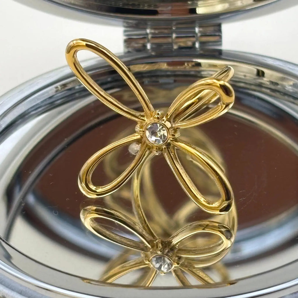 Bague de couleur dorée ajustable avec un motif de fleur a quatre pétales et strass en son centre