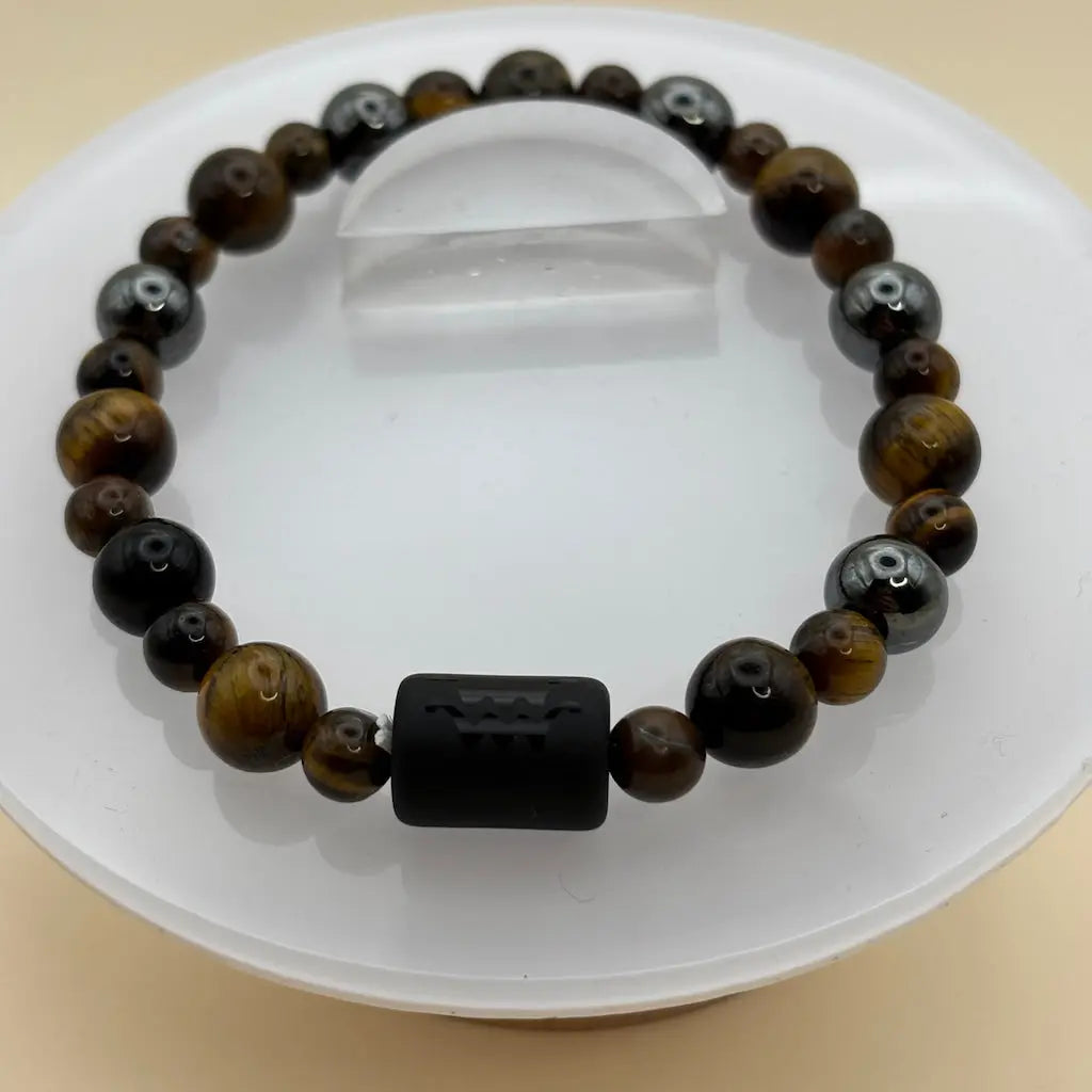 Bracelet composé de perles brunes et grises, accompagné d’un médaillon rond argenté au centre