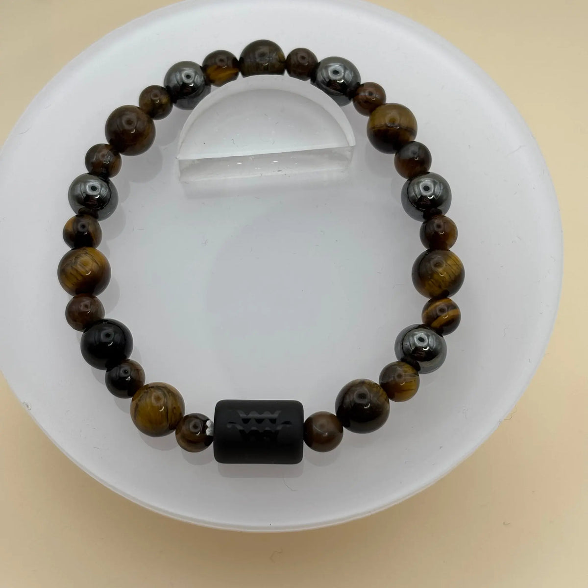 Bracelet de perles foncées avec un élément central cylindrique noir portant une gravure