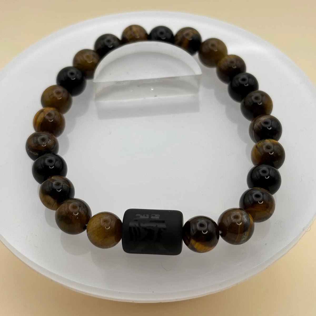 Bracelet de perles brun foncé avec une perle centrale cylindrique noire ornée d’une gravure