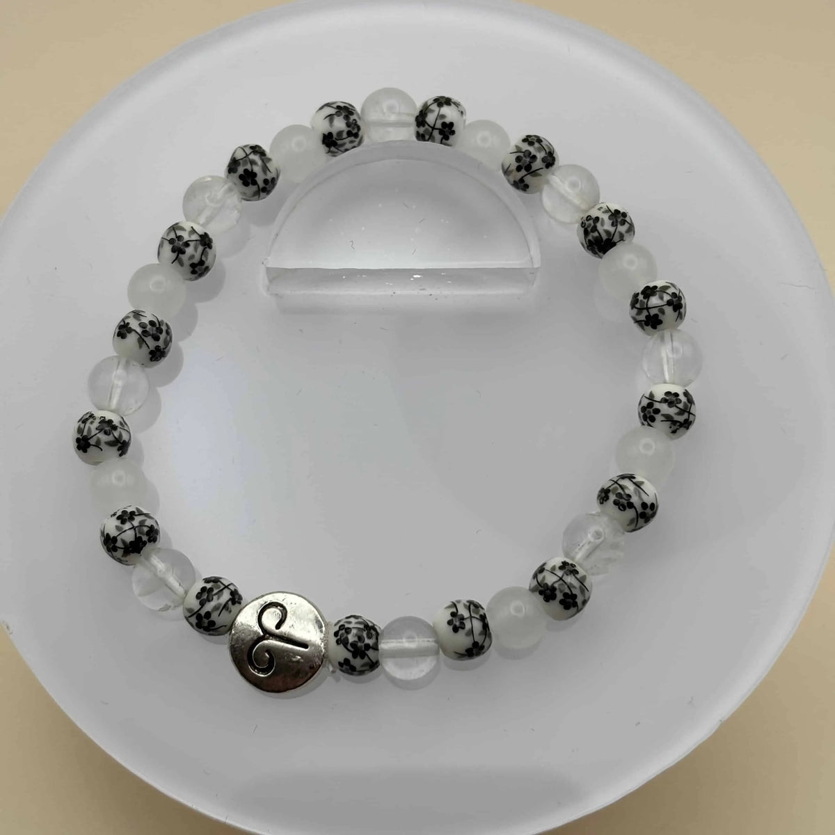 Un bracelet en perles sur élastique avec perles en porcelaine et en verre et médaillon signe du bélier