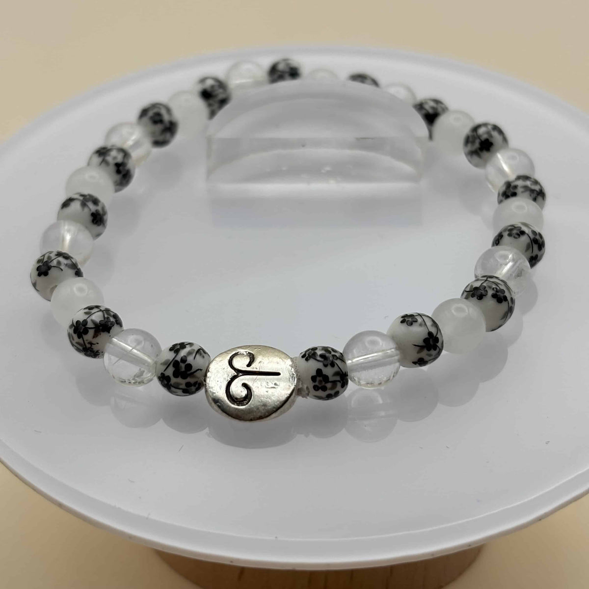 Un bracelet en perles sur élastique avec perles en porcelaine et en verre et médaillon avec le signe du bélier