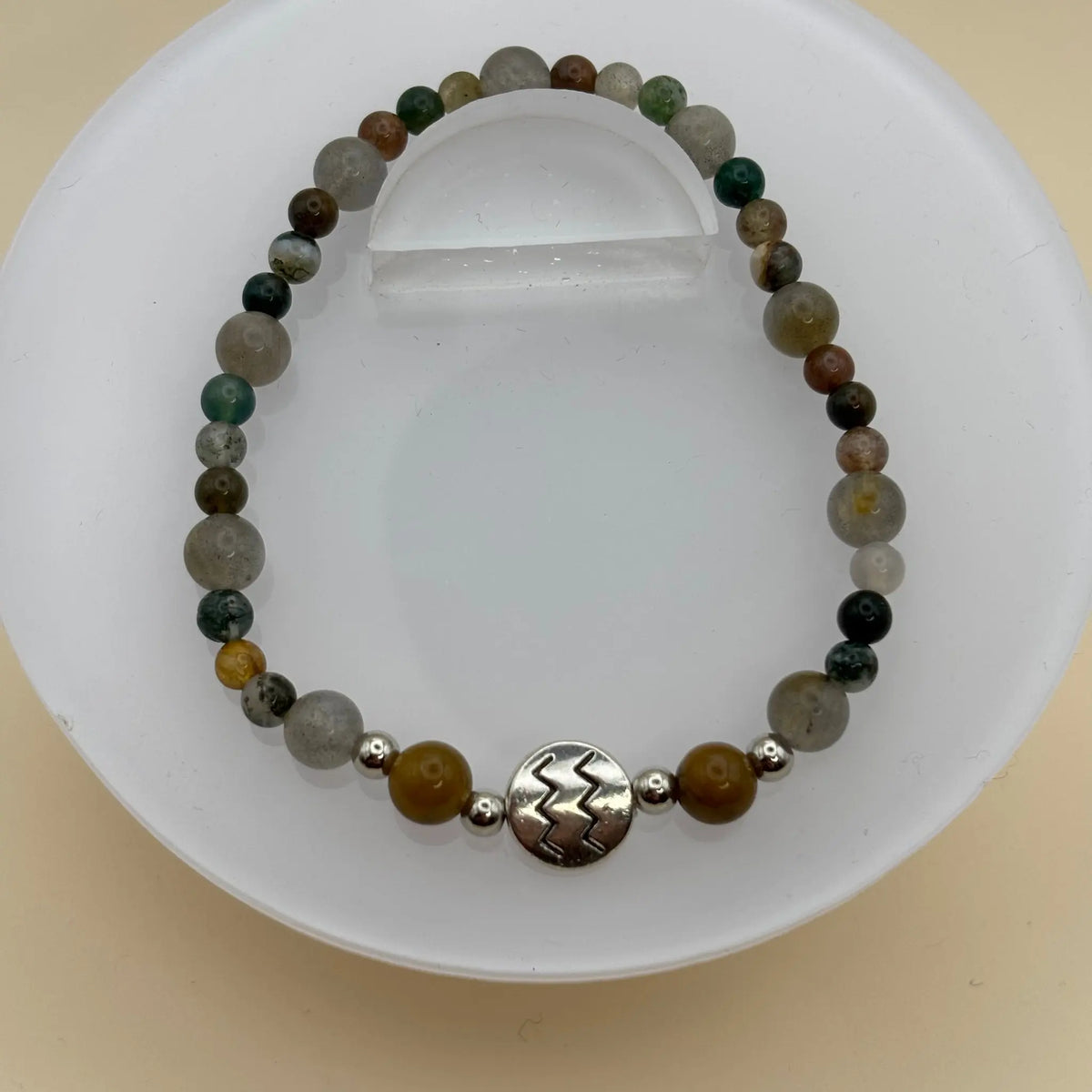 Bracelet aux perles brun clair et gris, décoré de petites perles argentées et d’un cylindre noir gravé au centre