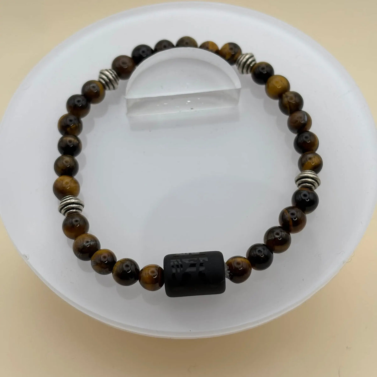 Bracelet combinant perles marron et perles hexagonales argentées, avec une perle centrale noire gravée