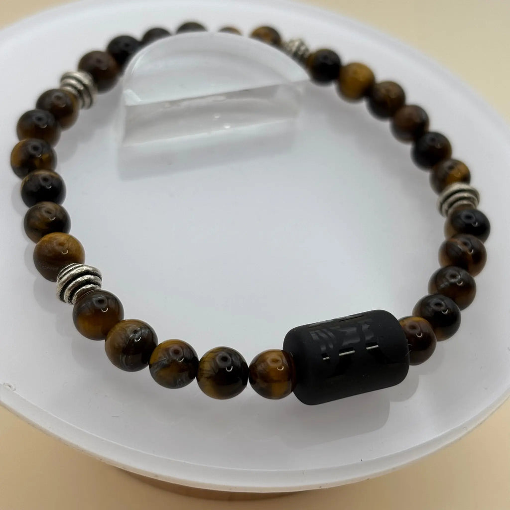 Bracelet aux perles mates marbrées brun clair, doté d’un cylindre noir gravé en élément central