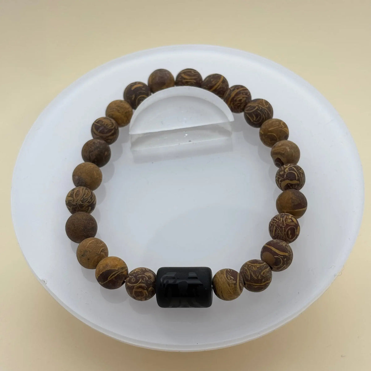 Bracelet alternant perles sombres et argentées, avec une perle centrale noire gravée