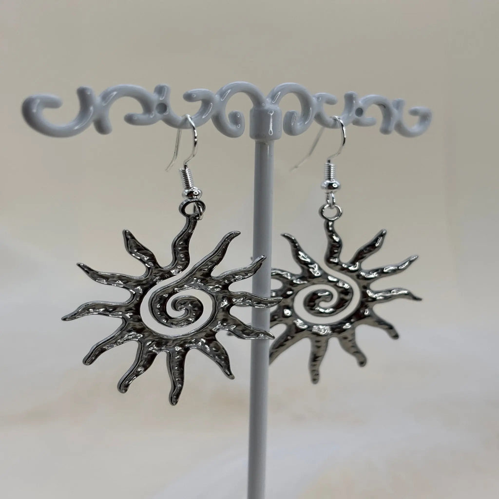 Une paire de boucles d'oreilles argentées avec motif de soleil spiralé