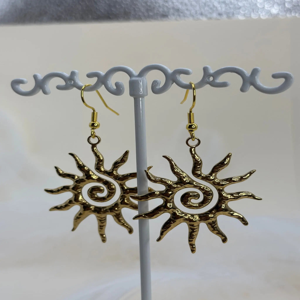 Une paire de boucles d'oreilles dorées avec motif de soleil spiralé