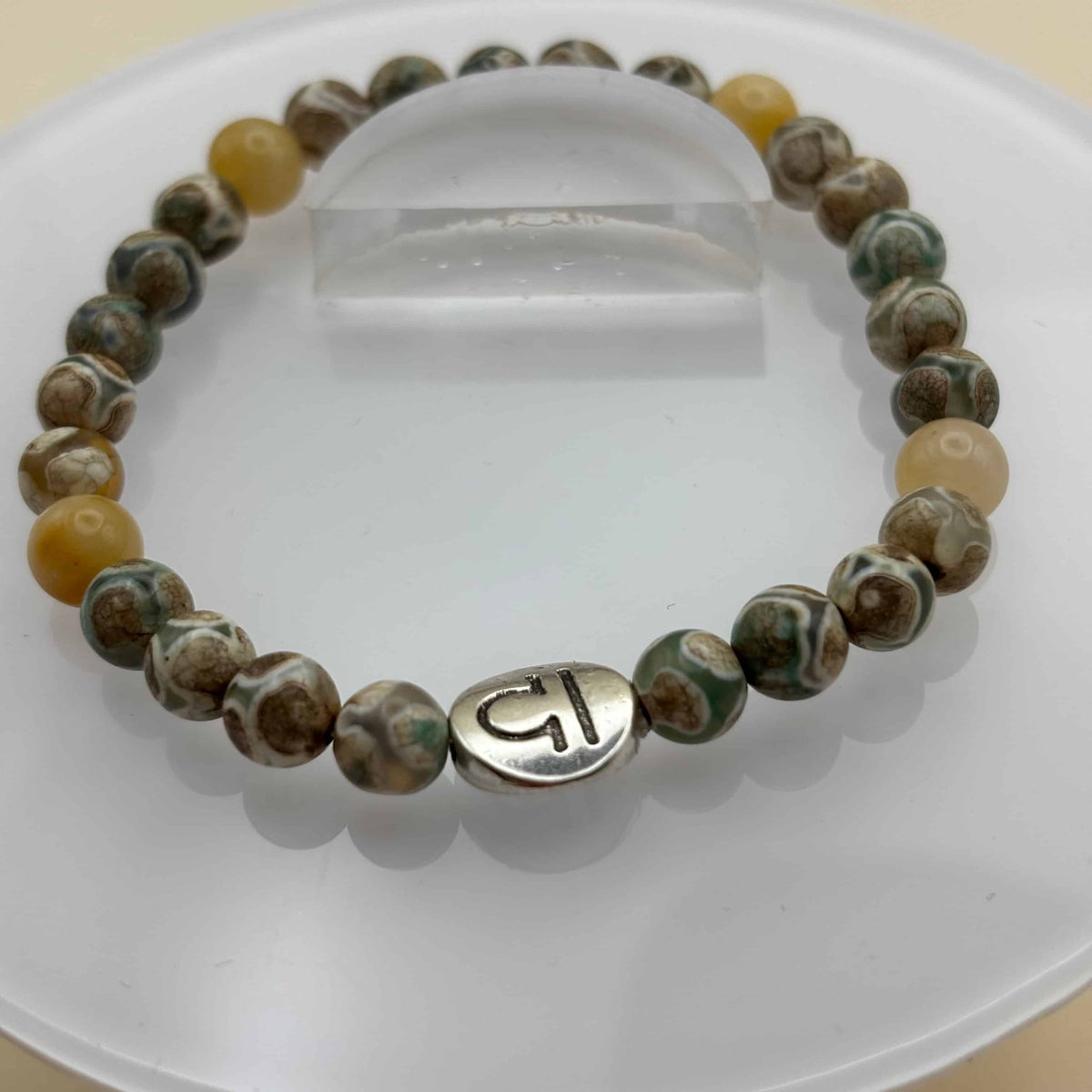 Un bracelet en perles sur élastique avec perles en porcelaine et en verre et médaillon avec le signe de la balance