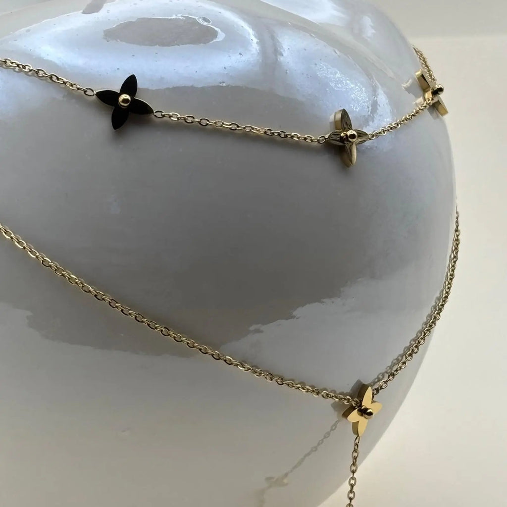 Un collier multirangs avec des étoiles dorées sur chainette et perle dorée en pendentif en acier inoxydable