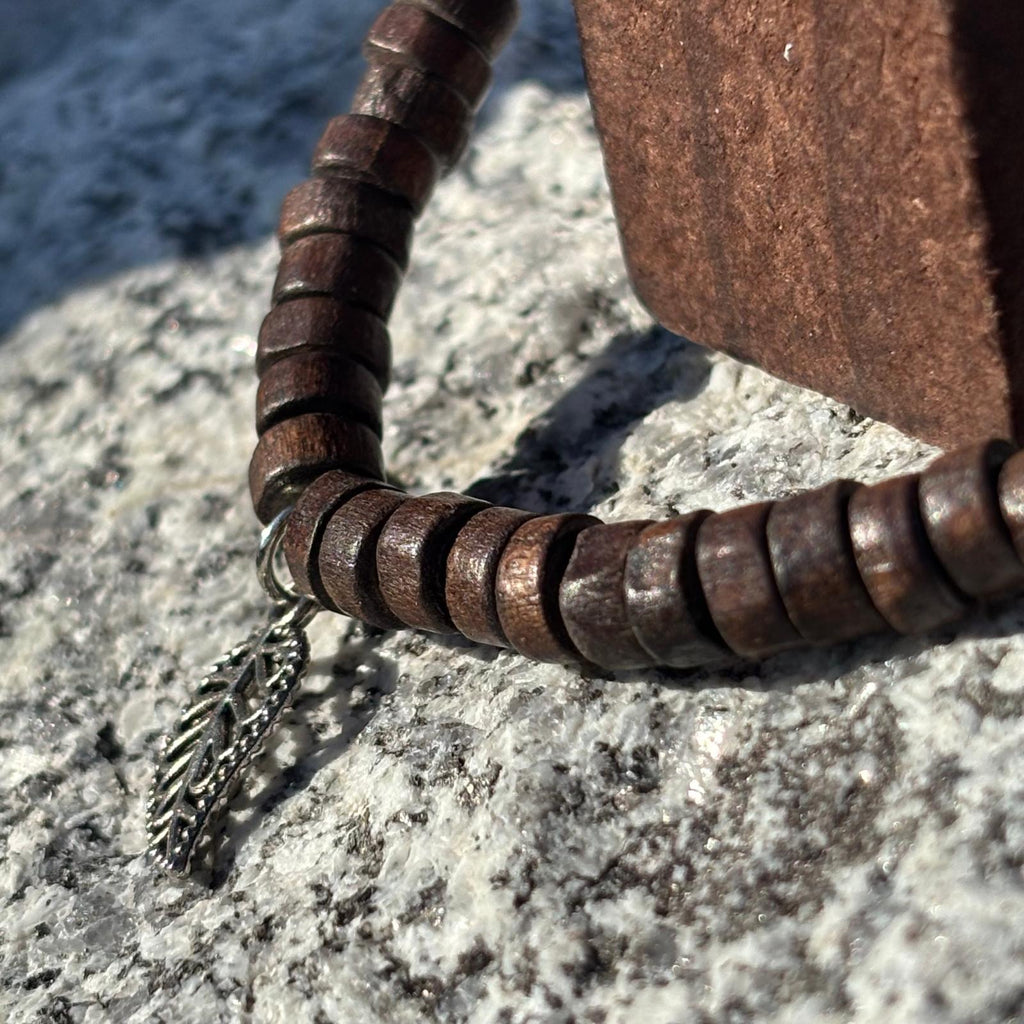 Vue de près d'un bracelet en perles artisanal avec breloques cœurs et perles plates en bois sur élastique