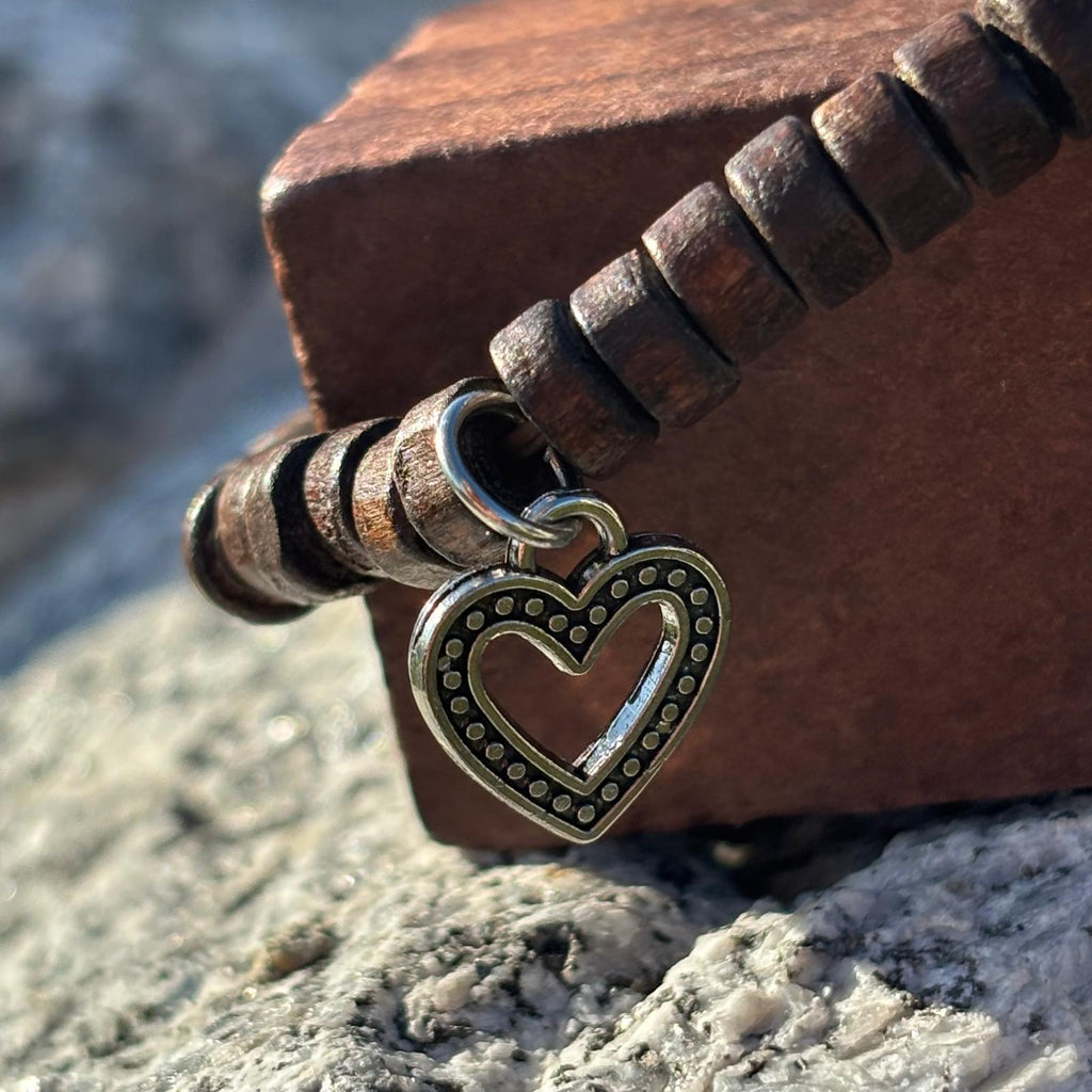 Vue de détail d'un bracelet en perles artisanal avec breloques cœurs et perles plates en bois sur élastique