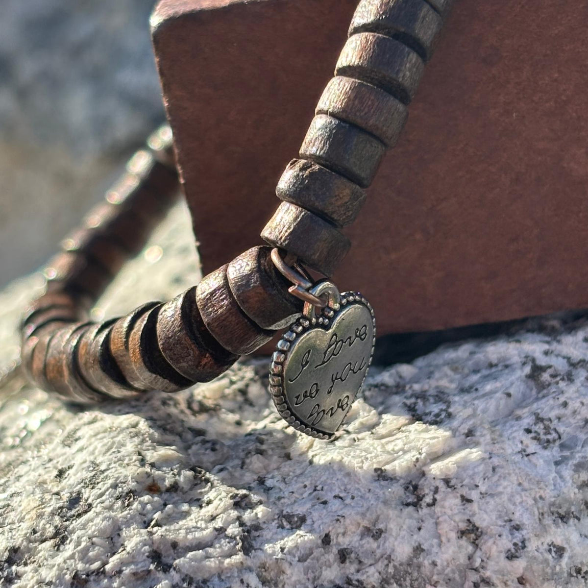 Vue détail d'un bracelet en perles artisanal avec breloques cœurs et perles plates en bois sur élastique