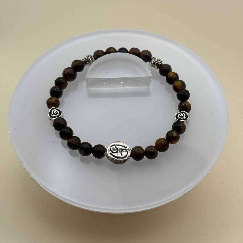 Un bracelet en perles sur élastique avec perles en porcelaine et en verre et médaillon avec le signe du cancer