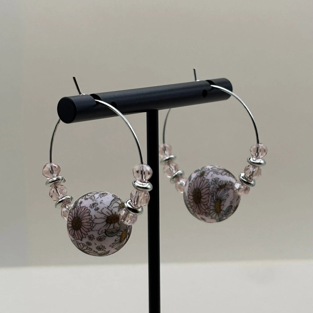 Des boucles d'oreilles artisanales créole  avec une perle acrylique fleurie et des perles roses