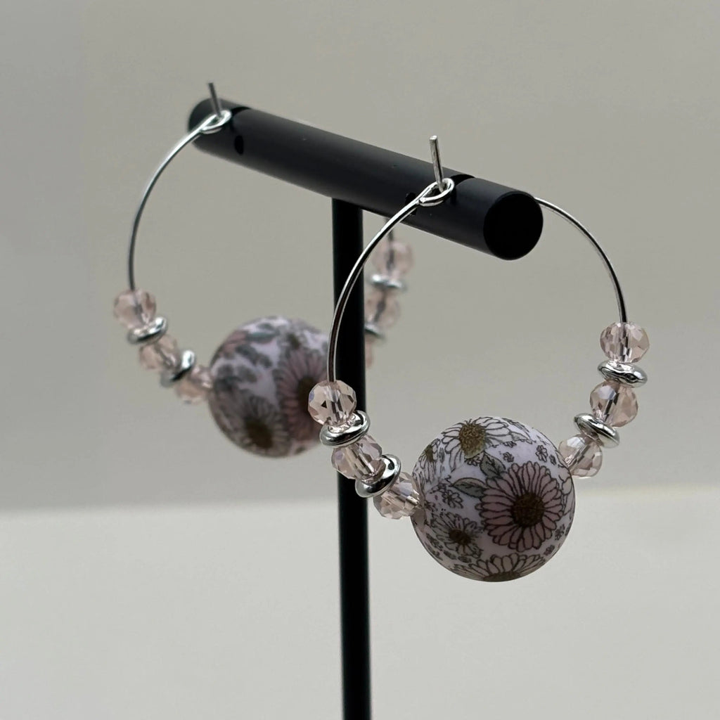 Une paire de boucles d'oreilles artisanales créole  avec une perle acrylique fleurie et des perles roses