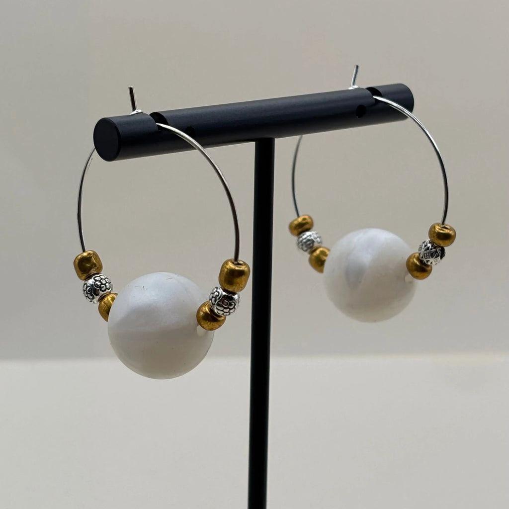 Des boucles d'oreilles créole avec une perle acrylique blanche et des petites perles dorées