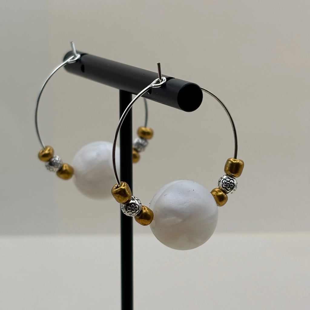 Une paire de boucles d'oreilles créole avec une perle acrylique blanche et des petites perles dorées