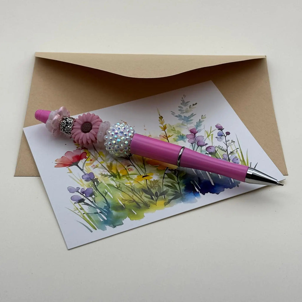 Stylo à bille noir corps rose orné d'une marguerite rose et de perles argentées