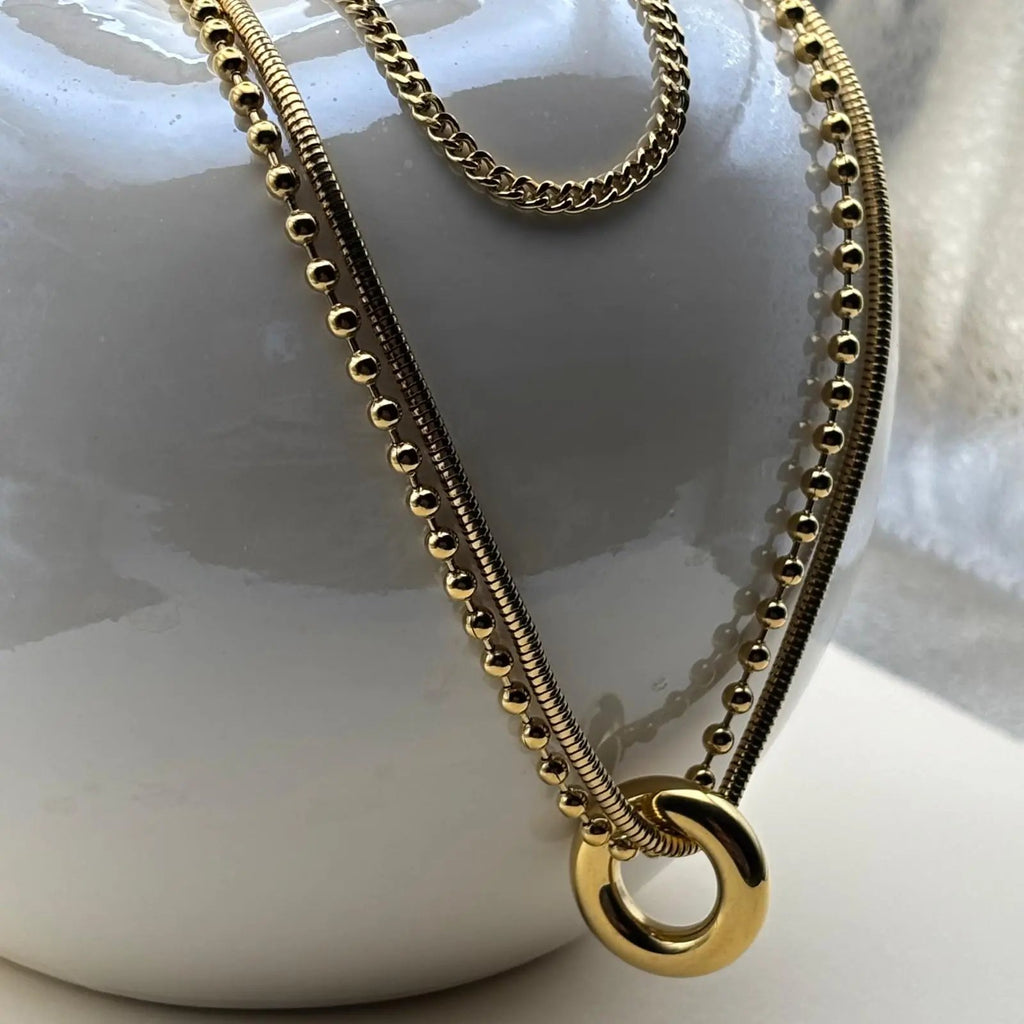 Collier multirangs avec trois chaînes dorées et un anneau doré relié à deux chaines en acier inoxydable 