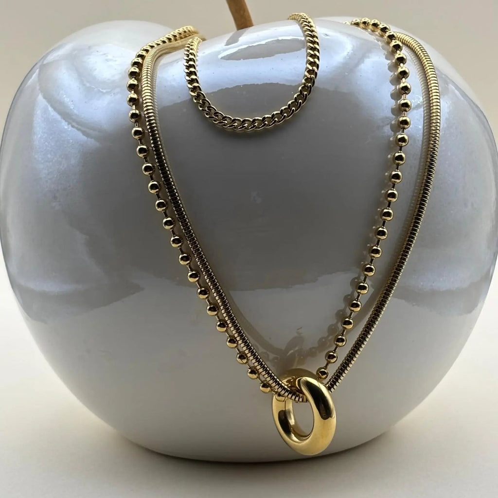 Collier multirangs avec trois chaînes dorées et un anneau doré relié à deux chaines qui sont en acier inoxydable 
