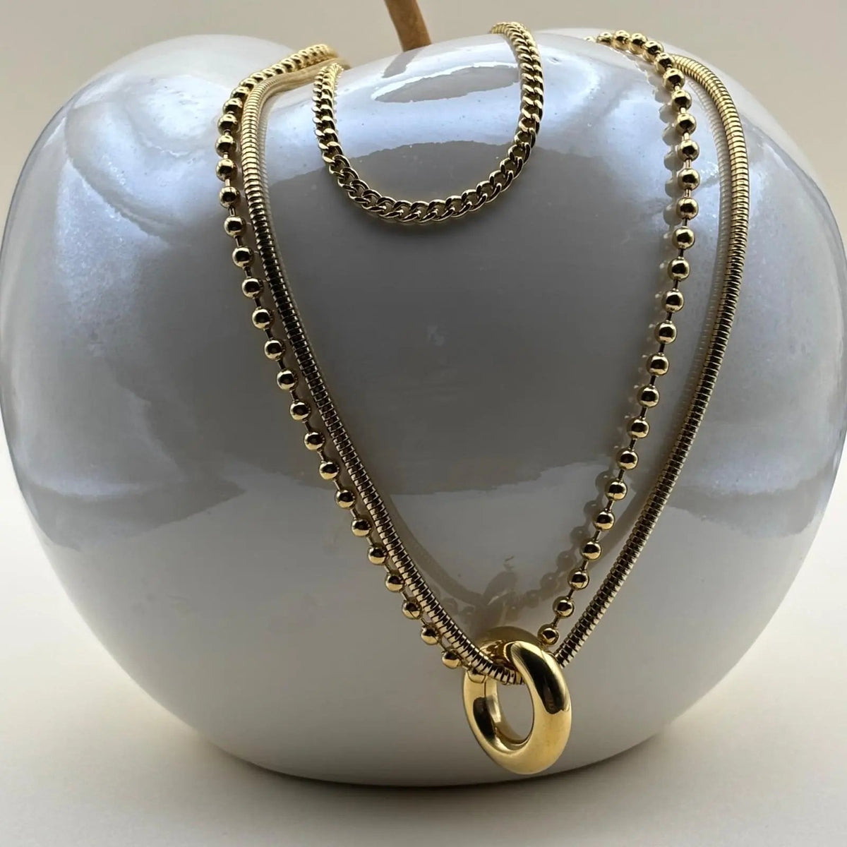 Collier multirangs avec trois chaînes dorées et un anneau doré relié à deux chaines qui sont en acier inoxydable 