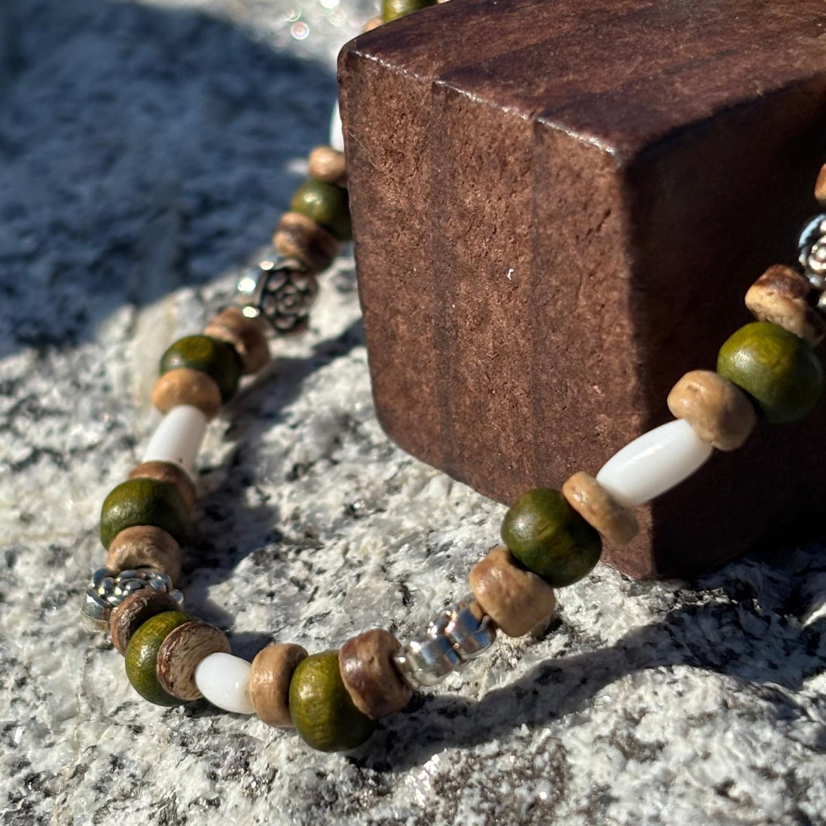 Vue de près d'un bracelet en perles artisanal avec breloque cœur et fleurs et des perles en bois sur élastique