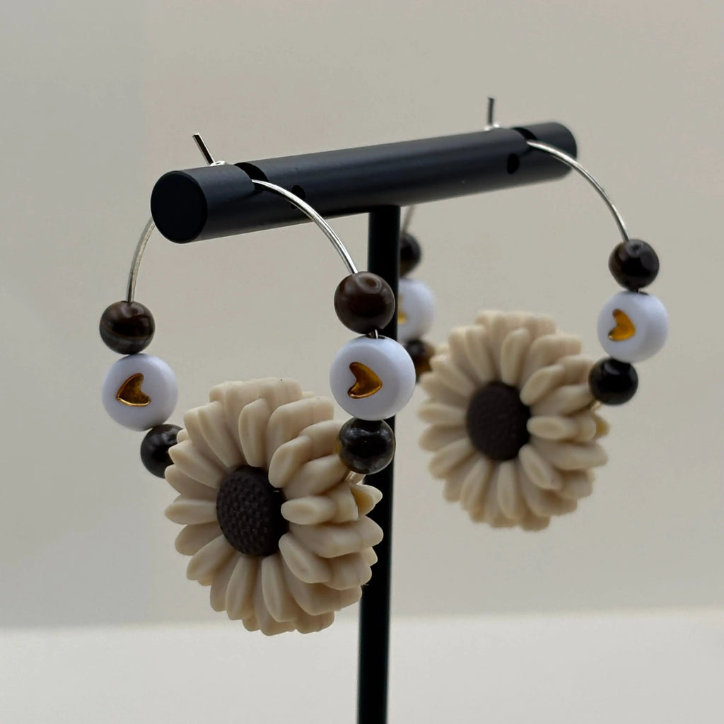Des boucles d'oreilles créole argentée avec breloque en forme de fleur blanche et quatre perles naturelles colorées