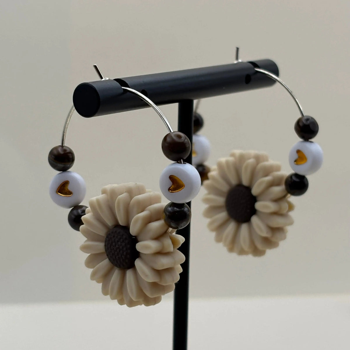 Des boucles d'oreilles créole argentée avec breloque en forme de fleur blanche et quatre perles naturelles colorées