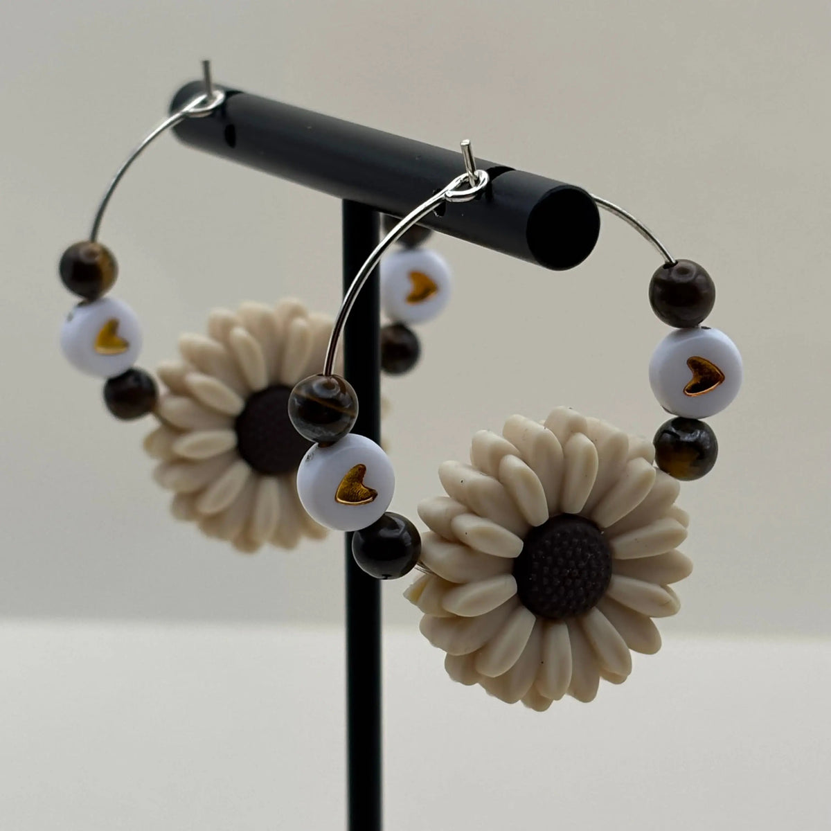 Une paire de boucles d'oreilles créole argentée avec breloque en forme de fleur blanche et quatre perles naturelles colorées