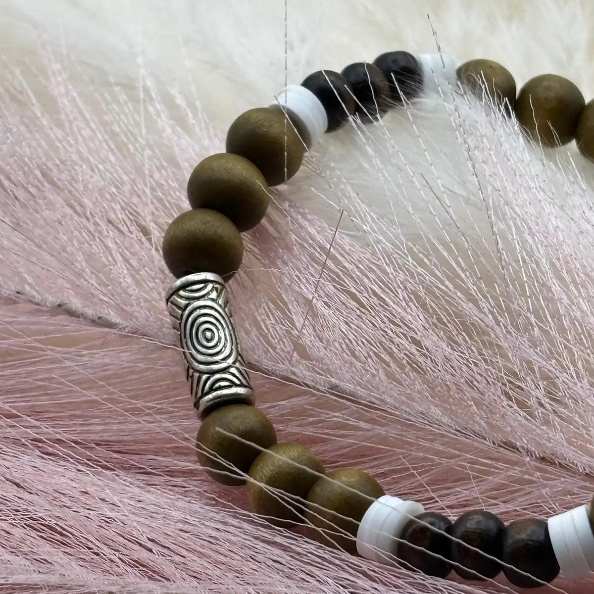 Vue de près d'un bracelet en perles artisanal avec perles de bois marron vert et perles acryliques allongées et rondes sur élastique