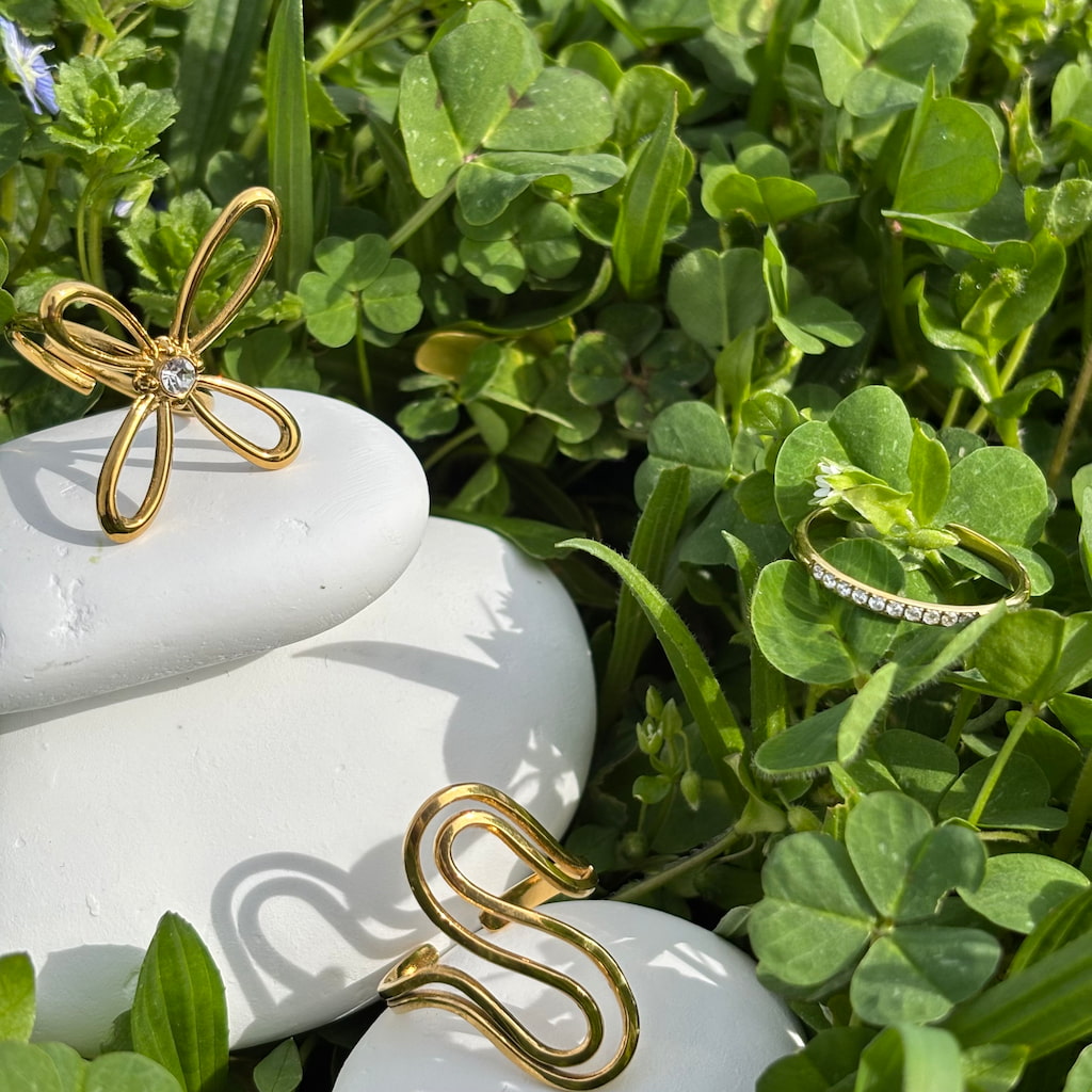 Des bagues fantaisie dorées sur un lit de trèfles