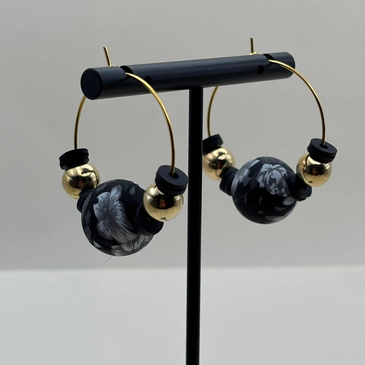 Des boucles d'oreilles créole artisanales dorées avec breloque colorée et perles dorées et noires
