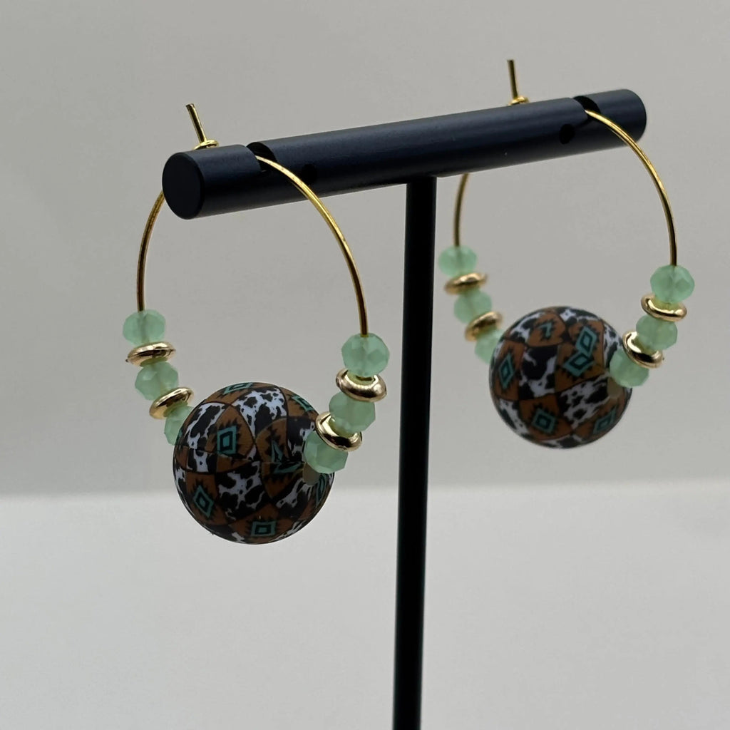 Des boucles d'oreilles créole artisanales dorées avec breloque centrale colorée et perles vert d'eau